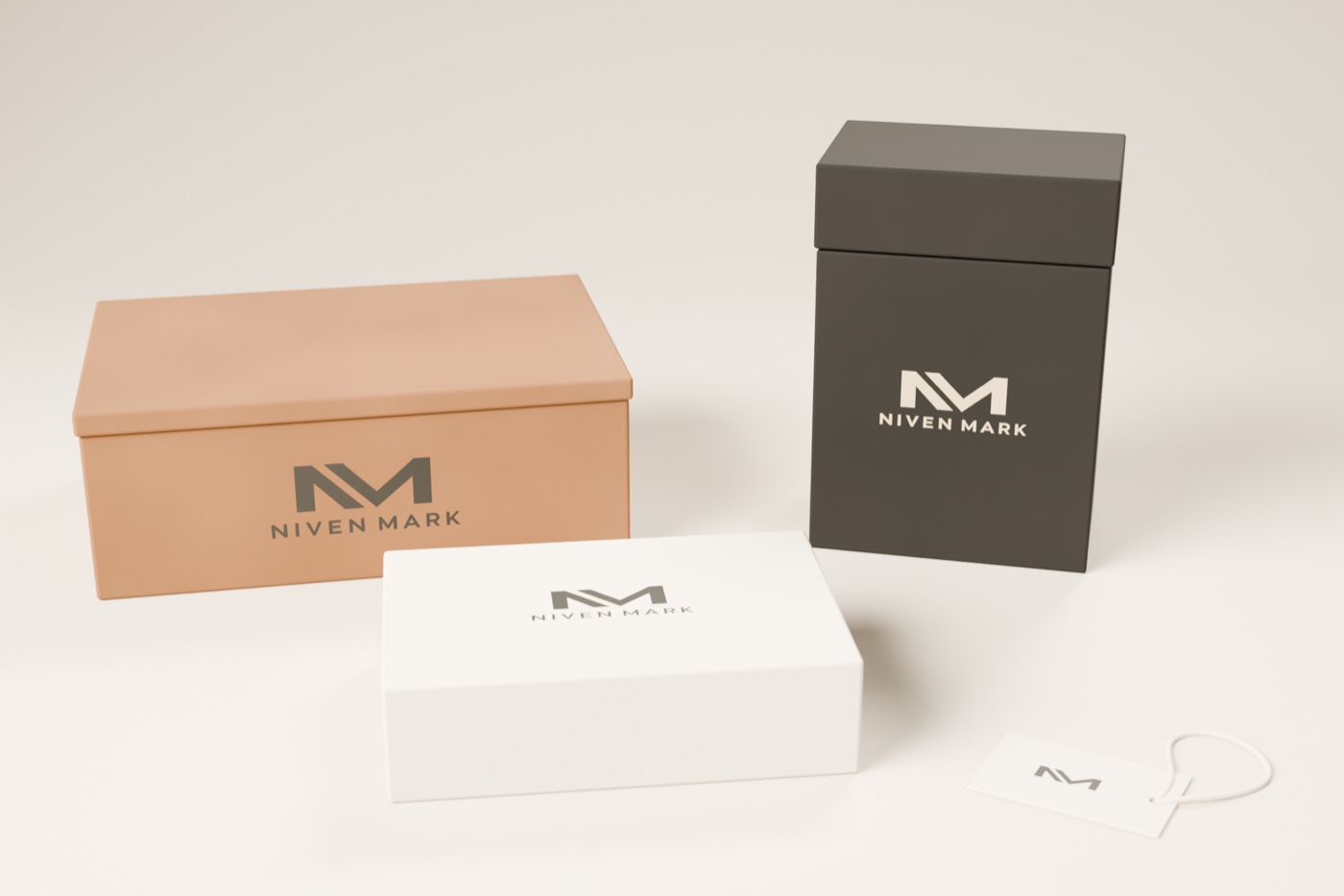 Sistema de empaque de Niven Mark: caja de envío kraft, cartón rígido carbón con tapa y el logotipo en crema, estuche crema y etiqueta colgante con el monograma y cordón, sobre una superficie clara.