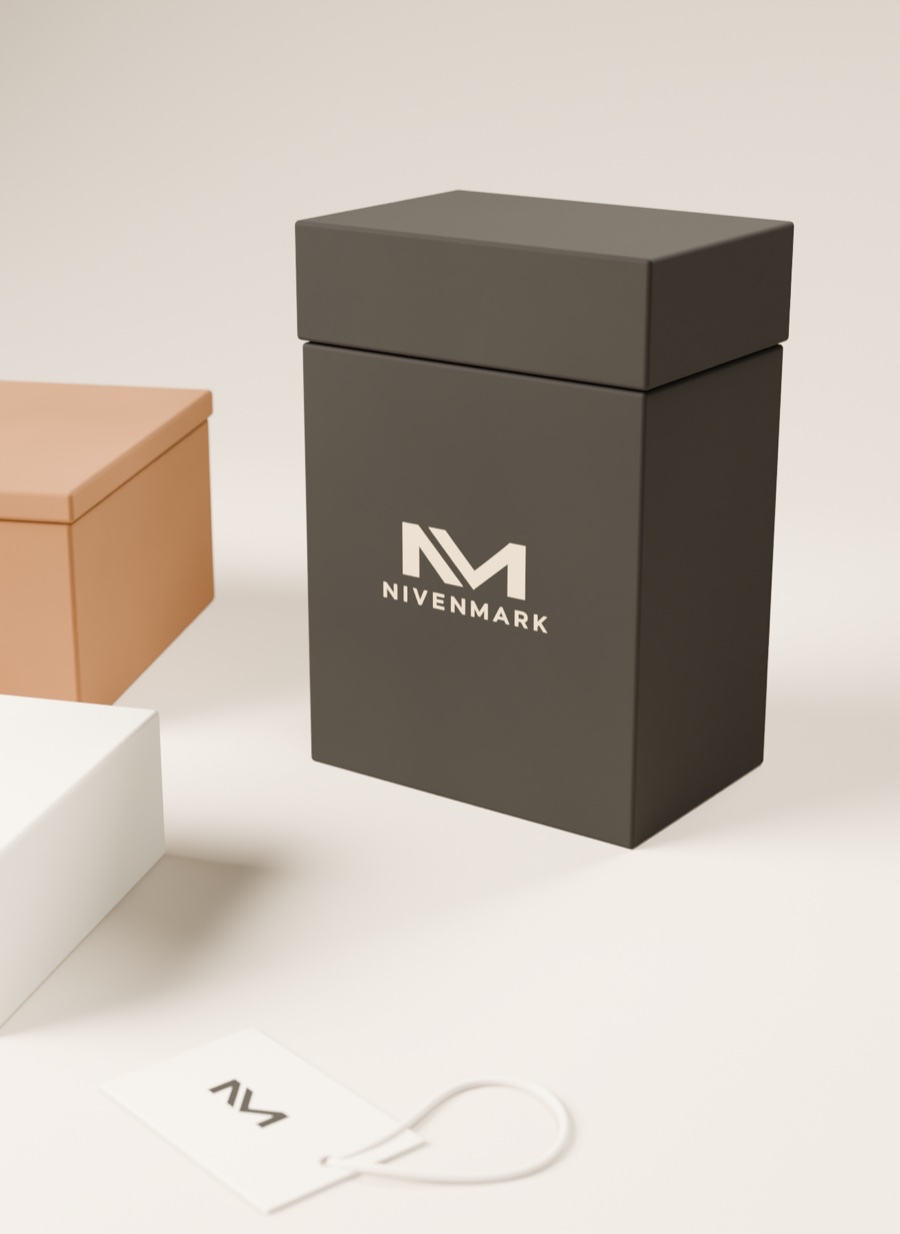 Detalle del cartón rígido carbón con tapa, el logotipo Nivenmark en crema y la etiqueta colgante con el monograma.