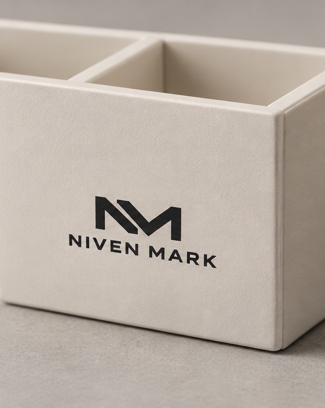 Logotipo Niven Mark impreso en negro sobre la cara de un organizador de escritorio de cartón rígido crema.